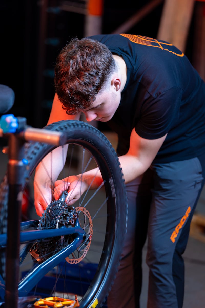 Focused teenager repairing a bicycle wheel in an indoor garage setting.