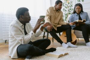 Three people engaged in a bible study discussion together inside a cozy room.