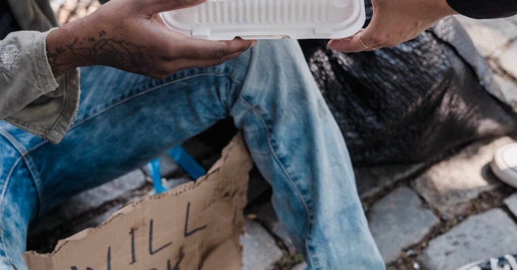 A compassionate act of giving food to a homeless person sitting on a city sidewalk.